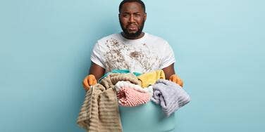 Man crying while holding laundry hamper.